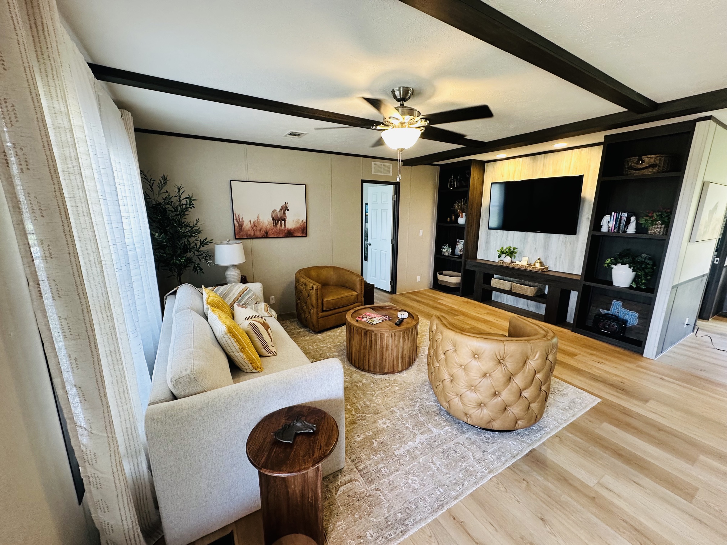 Open living room with beamed ceiling and built-ins